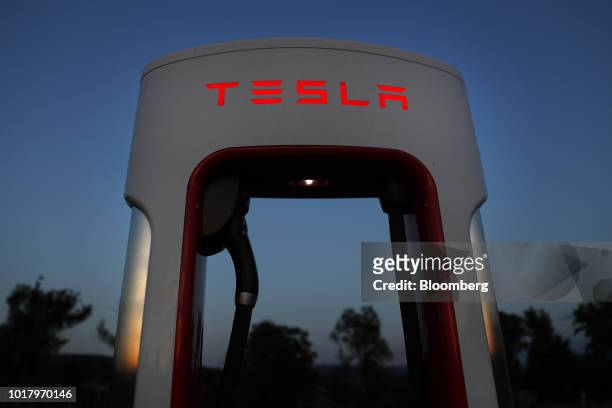 Tesla Inc. Supercharger station stands illuminated at dusk in Rubigen, Switzerland, on Thursday, Aug. 16, 2018. Tesla chief executive officer Elon...