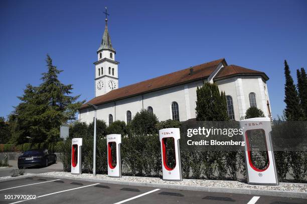 Tesla Inc. Supercharger stations stand in front of the parish church in Kriegstetten, Switzerland, on Thursday, Aug. 16, 2018. Tesla chief executive...