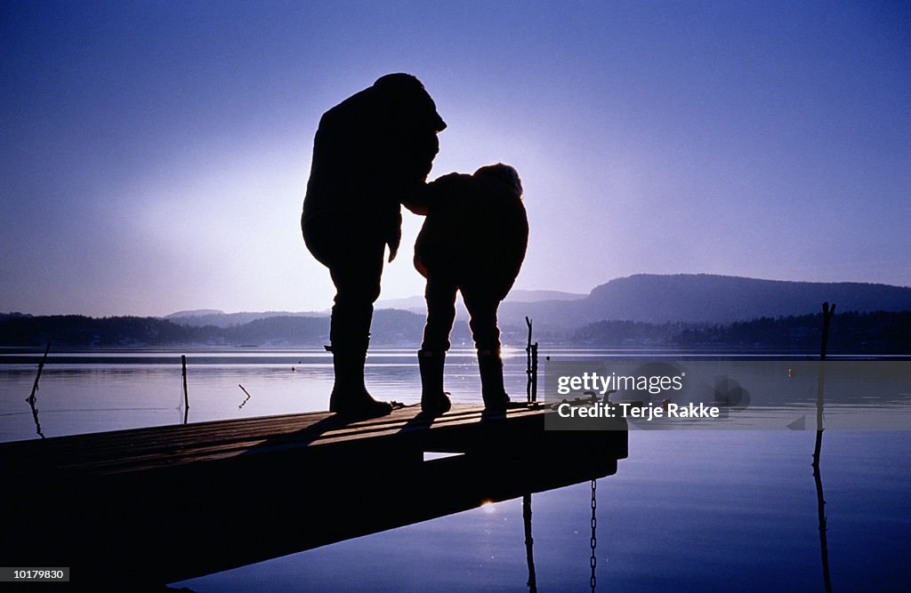 MOM & CHILD LOOKING AT FISH IN SEA