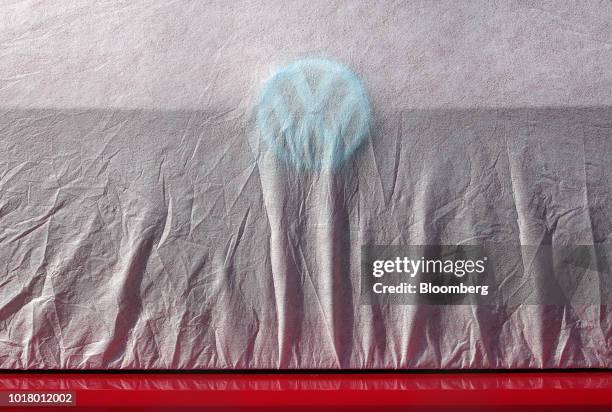 Protective cover rests over a badge on a new Volkswagen AG automobile, stockpiled in a parking lot at Willy Brandt Berlin Brandenburg International...