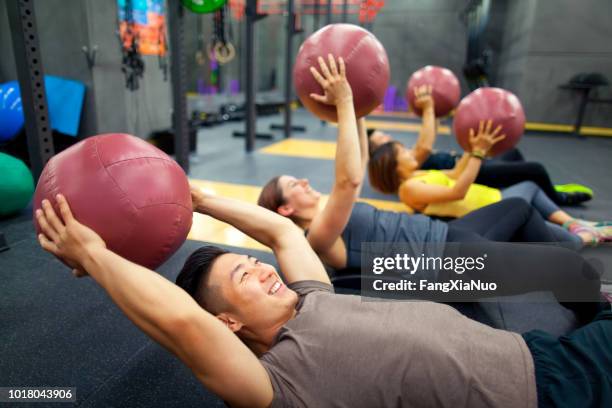 young people lifting exercise ball in exercise class - medicine ball stock pictures, royalty-free photos & images