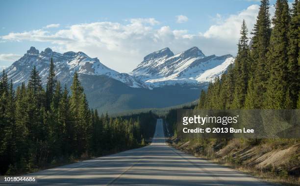 a long straight road into the snow-topped mountain - banff national park fotografías e imágenes de stock