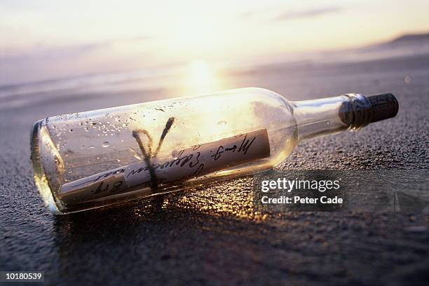 message in bottle on beach at sunset - message in a bottle stock pictures, royalty-free photos & images