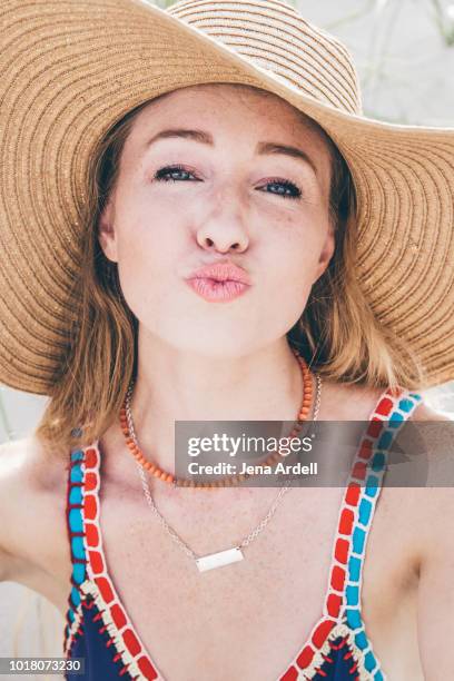 woman kissy face, woman wearing beach hat, woman wearing sun hat, sun protection, woman fair complexion, woman fair skin - pale complexion stock-fotos und bilder
