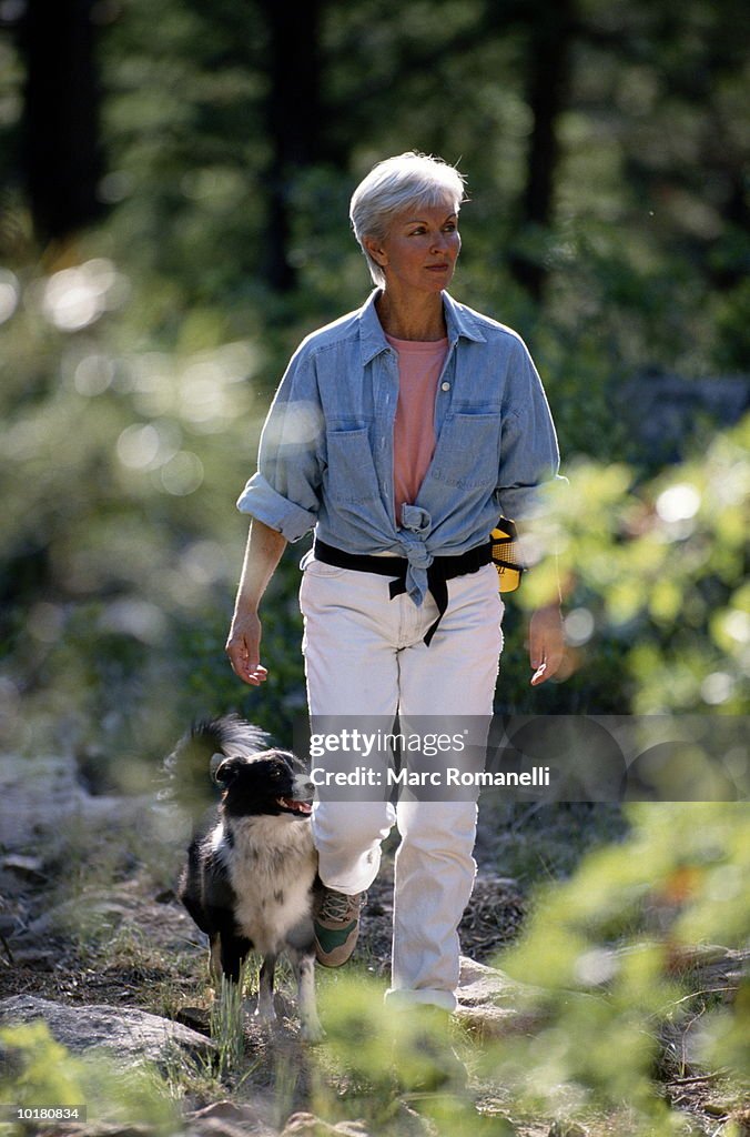 MATURE WOMAN HIKING WITH DOG