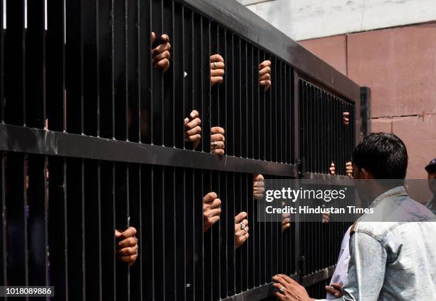 Workers wait at the gate to get a glimpse of the mortal remains of Atal Bihari Vajpayee at the BJP headquarters, on August 17, 2018 in New Delhi,...