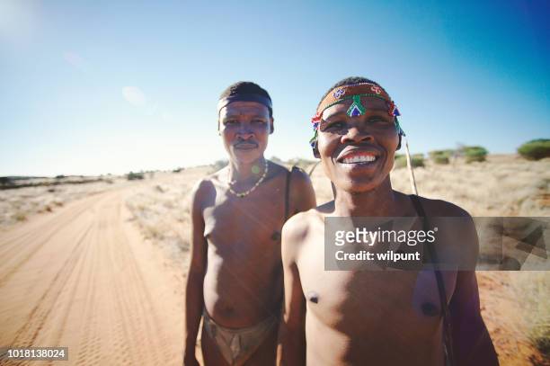portrait hunters bushmen san namibia standing on a sandy dirt road looking at camera - boxímane imagens e fotografias de stock