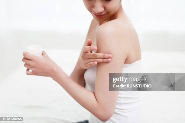 close up of young woman applying cream on arm - japanese ethnicity the human body stock pictures, royalty-free photos & images