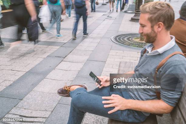 jongeman zit op een bankje van het tekstoverseinen in de straten van parijs - the weekend in news around the world stockfoto's en -beelden