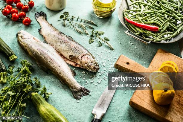 raw fish trout on the kitchen table with ingredients for cooking - trout stock pictures, royalty-free photos & images