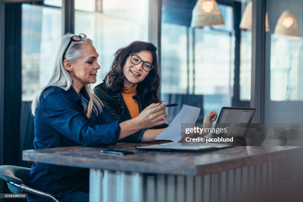 Two women analyzing documents at office