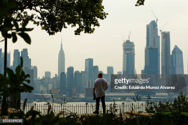 Man takes a look of the haze over the New York skyline and Empire State Building on August 17, 2018 in Weehawken, New Jersey. Severe thunderstorms...