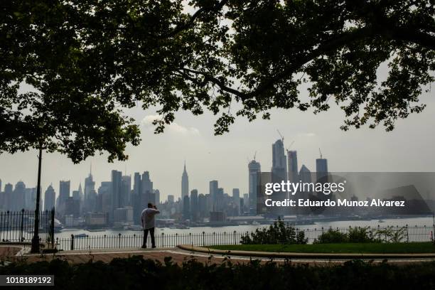 Man takes a look of the haze over the New York skyline and Empire State Building on August 17, 2018 in Weehawken, New Jersey. Severe thunderstorms...