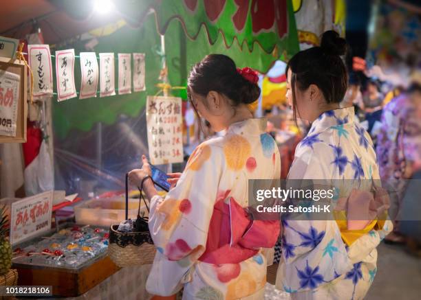 junge freundinnen im yukata einkaufen auf japanische yatai markt in festival - marktstand stock-fotos und bilder