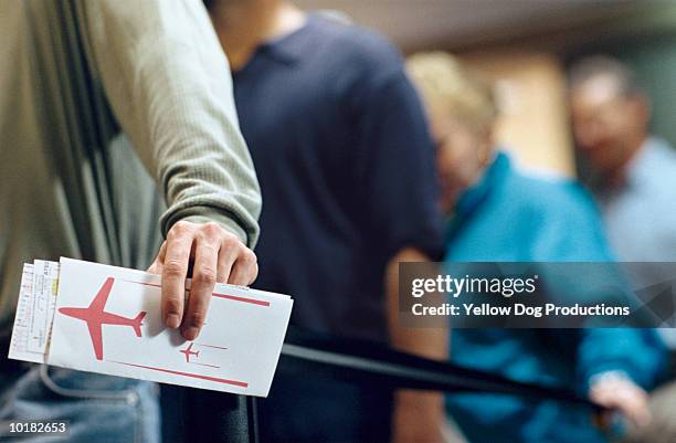 man holding ticket in airline check in line - passagem de avião - fotografias e filmes do acervo