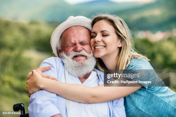 young woman and a senior man in wheelchair standing outdoors in the garden, hugging. - slovakia country stock pictures, royalty-free photos & images