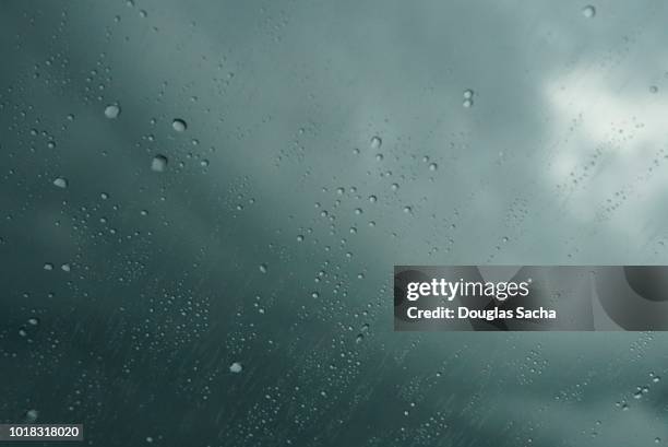 rain drops on the window while watching the dark storm clouds - 結露　ガラス ストックフォトと画像