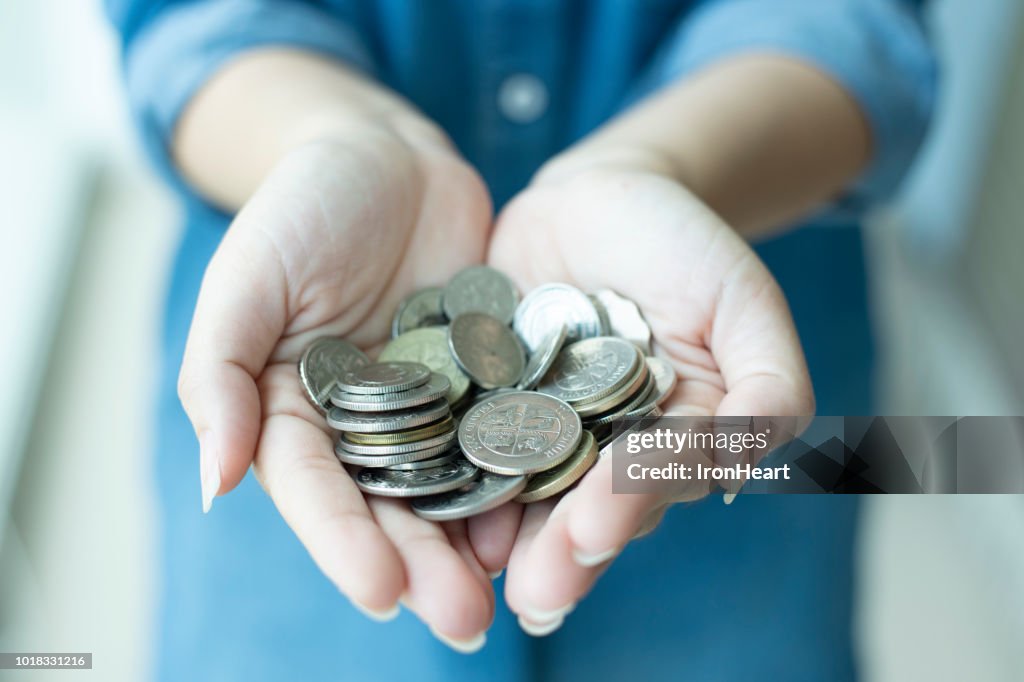 Woman is hand on coins as for saving money.