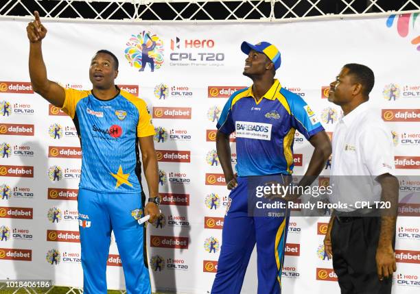 In this handout image provided by CPL T20, Kieron Pollard of St Lucia Stars toss the coin as Jason Holder of Barbados Tridents and match referee...