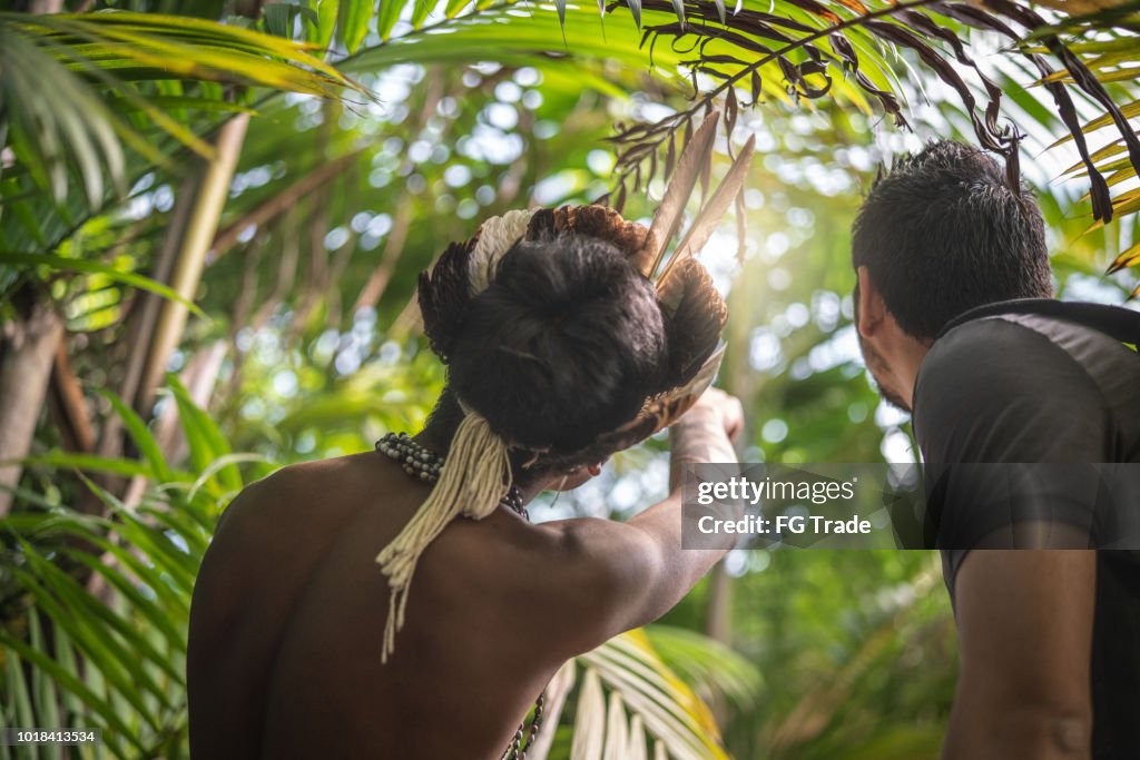 Indigenous Brazilian Young Man from Guarani ethnicity Showing the Rainforest to Tourist