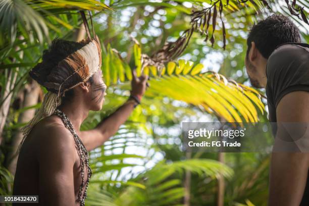 indigenous brazilian young man from guarani ethnicity showing the rainforest to tourist - amazonas state brazil stock pictures, royalty-free photos & images