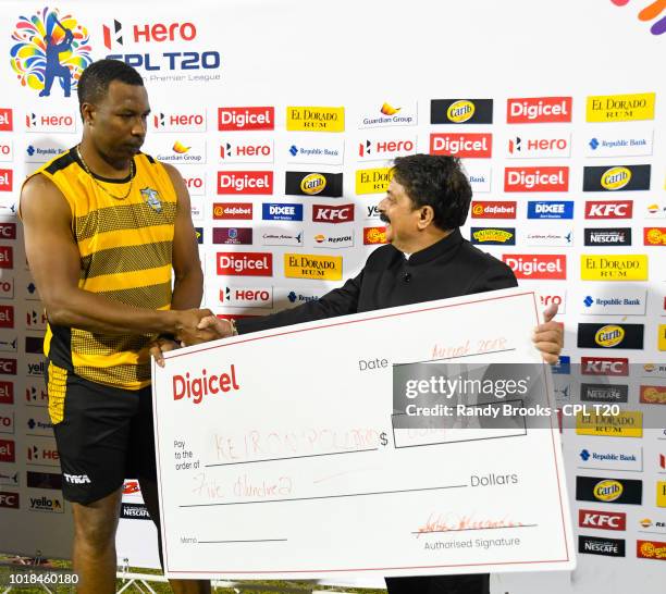 In this handout image provided by CPL T20, Kieron Pollard of St Lucia Stars receives the man of the match prize from Rajendra Trivedi at the end of...