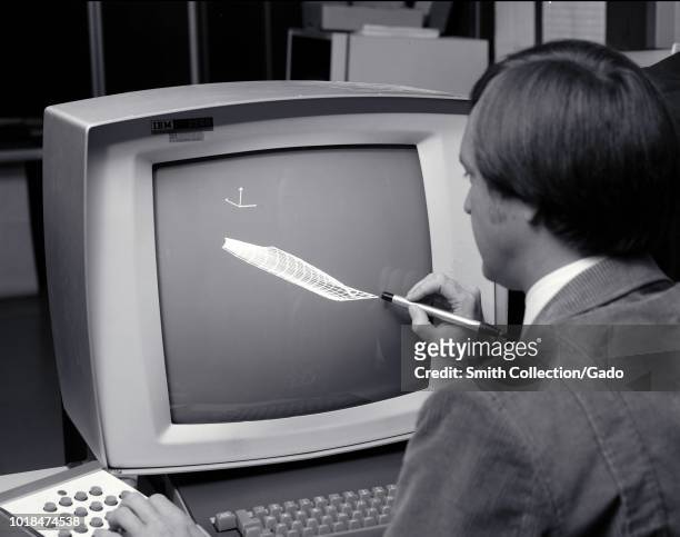 Black and white photograph of Paul Kutler, using a light pen and keyboard to work on a vector graphics project using an IBM 2250 Graphics Display...