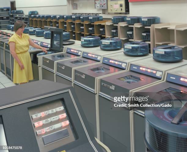 Color photograph of a female researcher, adjusting a component on a computer inside the Nasa Ames Research Center's Central Computer Facility N-233,...