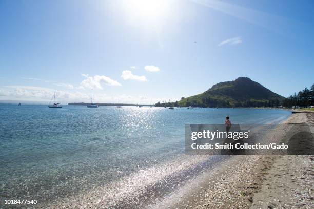 Boy standing on a seashore under the Mount Maunganui in Tauranga Harbor, North Island, New Zealand, October 30, 2017.