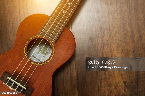 a ukulele on brown wooden background. - ukulele stock-fotos und bilder