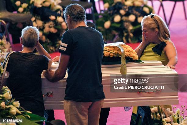 Relatives mourn near the coffins of some of the victims of the collapsed Morandi highway bridge, laid in front of the altar, prior to the start of...