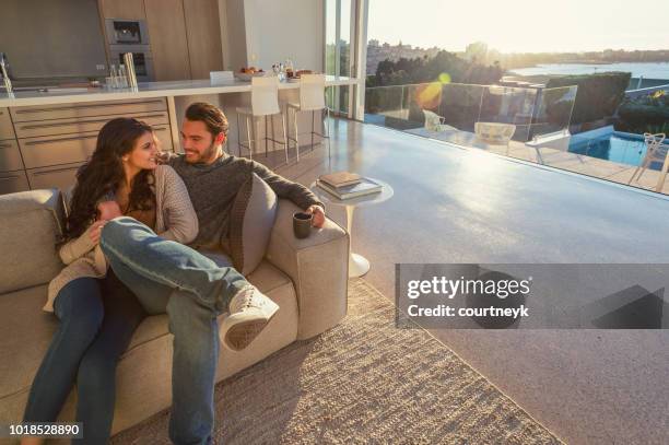 couple on the sofa at sunrise. they both have a cup of coffee. - living room young couple stock pictures, royalty-free photos & images