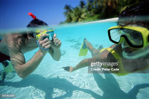 man taking photograph of woman underwater - macchina fotografica subacquea foto e immagini stock