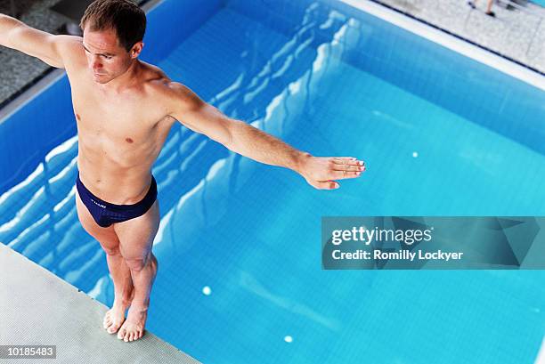 male swimmer on diving board preparing to dive - in het water duiken stockfoto's en -beelden