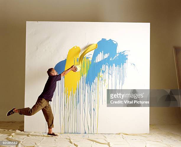 artist throwing paint at canvas - creatività foto e immagini stock