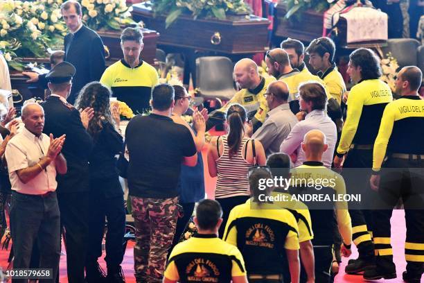 Relatives of the victims of the collapsed Morandi highway bridge applaud Italian firefighters as they arrive to pay their respects at the start of...