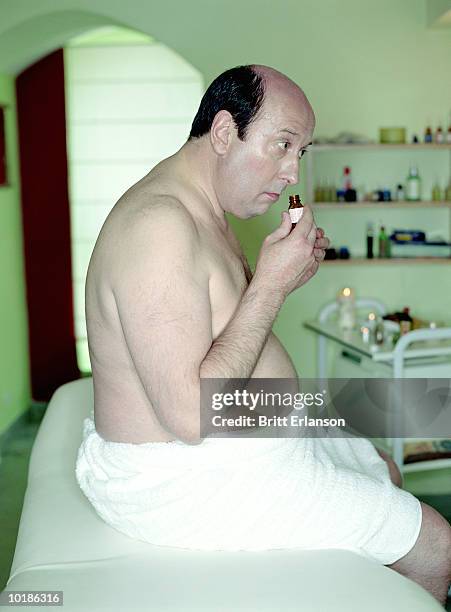 man smelling oil in massage room - fat massage stock pictures, royalty-free photos & images