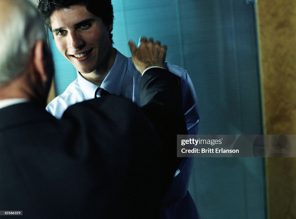 MAN PATTING YOUNG EXECUTIVE ON SHOULDER