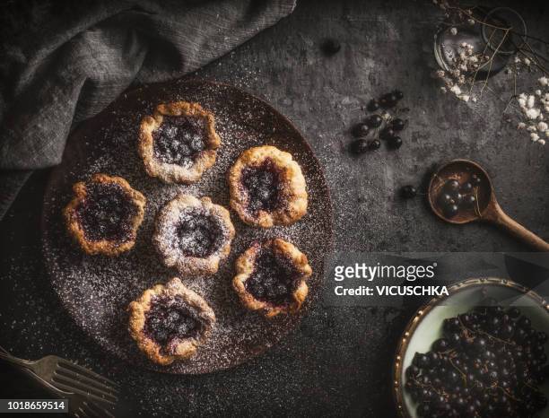 Small cakes on wooden plate with a black currant and jam