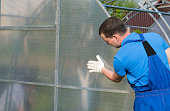 workers in blue uniforms, checking the correct installation of the greenhouse and polycarbonate on it.