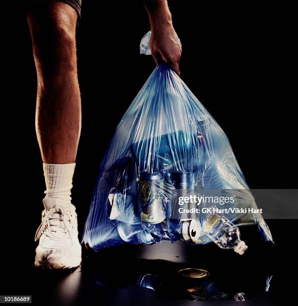 man taking out torn garbage bag - man wrapped in plastic stock pictures, royalty-free photos & images