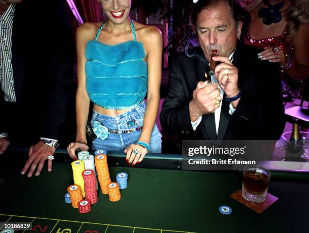 mature man in casino lighting cigar - super rich stock-fotos und bilder