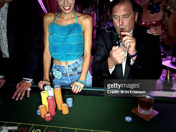 mature man in casino lighting cigar - roulette stock pictures, royalty-free photos & images