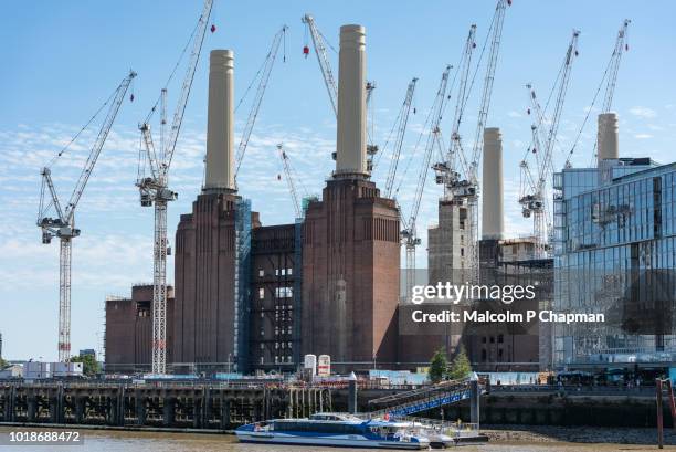 cranes surround battersea power station, london, seen from across the river thames. - battersea power station stock-fotos und bilder