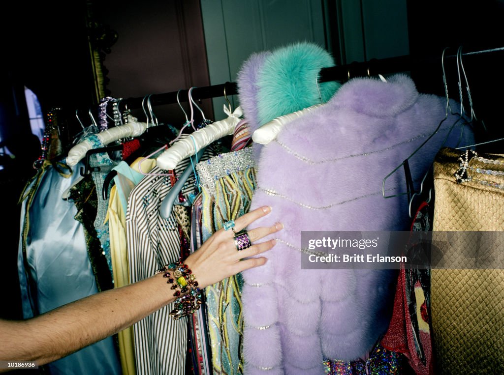 WOMAN SELECTING CLOTHES FROM RAIL, CLOSE-UP