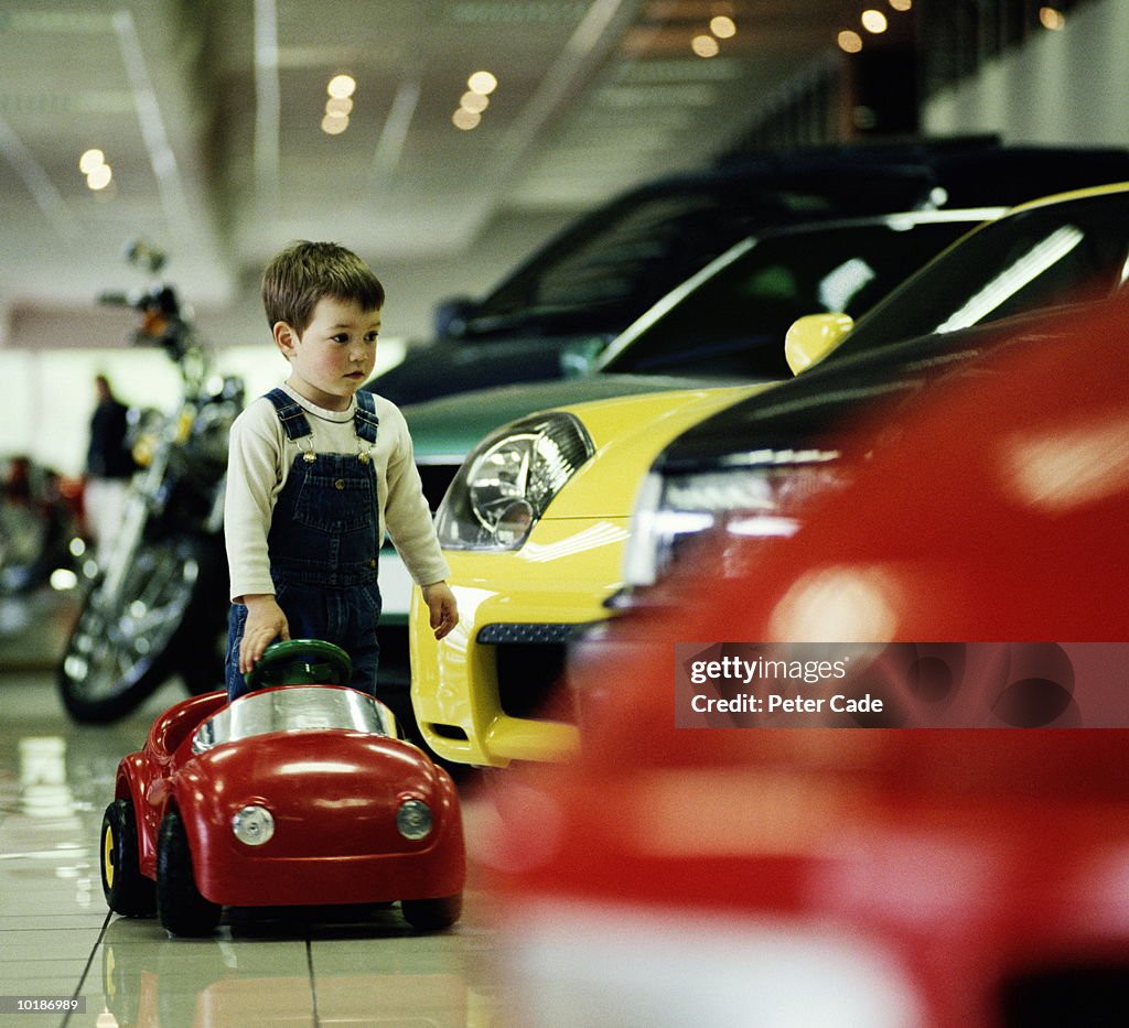 BOY (3-5) WITH TOY CAR IN CAR SHOWROOM