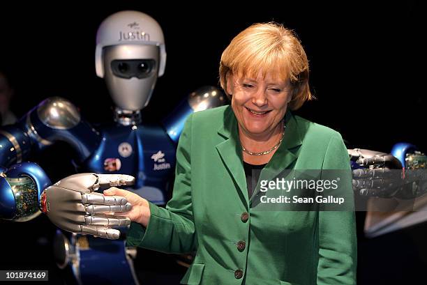 German Chancellor Angela Merkel poses with "Justin," a robot at the space travel pavillion at the ILA Berlin Air Show on June 8, 2010 in Berlin,...