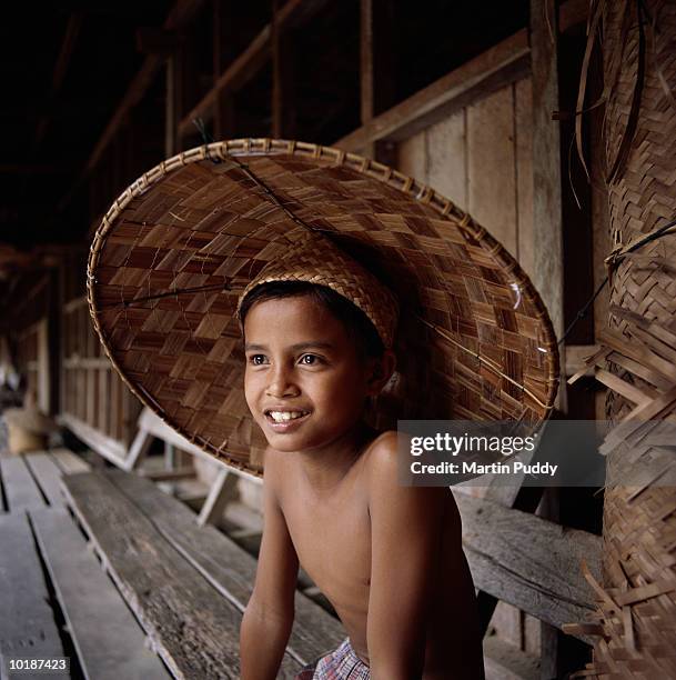 malaysia, sarawak, iban boy (7-9) wearing hat - longhouse 個照片及圖片檔