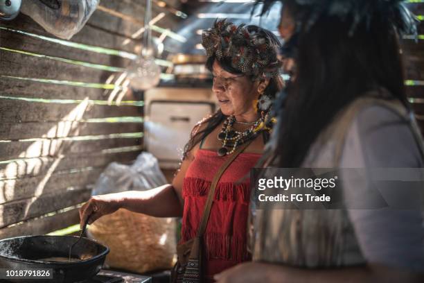 indigene brasilianerinnen von guarani ethnizität, kochen "xipa" - village home indoor stock-fotos und bilder