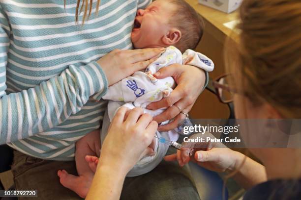 baby boy having injection into leg - vaccine uk stock pictures, royalty-free photos & images